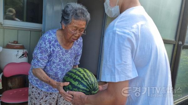 [크기변환](사진) 면 관계자가 양지제일교회에서 기탁받은 수박을 한 홀로어르신 가정에 전달하고 있다..jpg