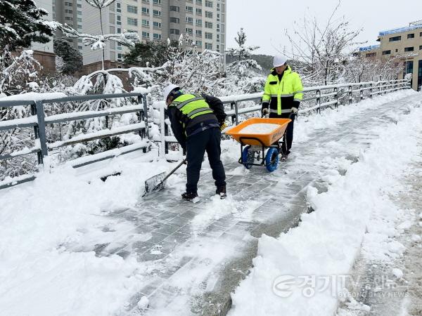 [크기변환]2. 시 관계자가 인도에 쌓인 눈을 치우며 소형 제설장비로 염화칼슘을 뿌리고 있다.jpg